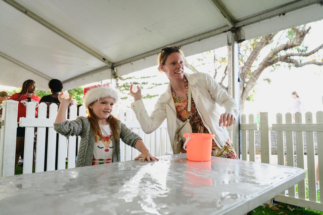 A mother and daughter hold snowballs and take aim to throw them at targets